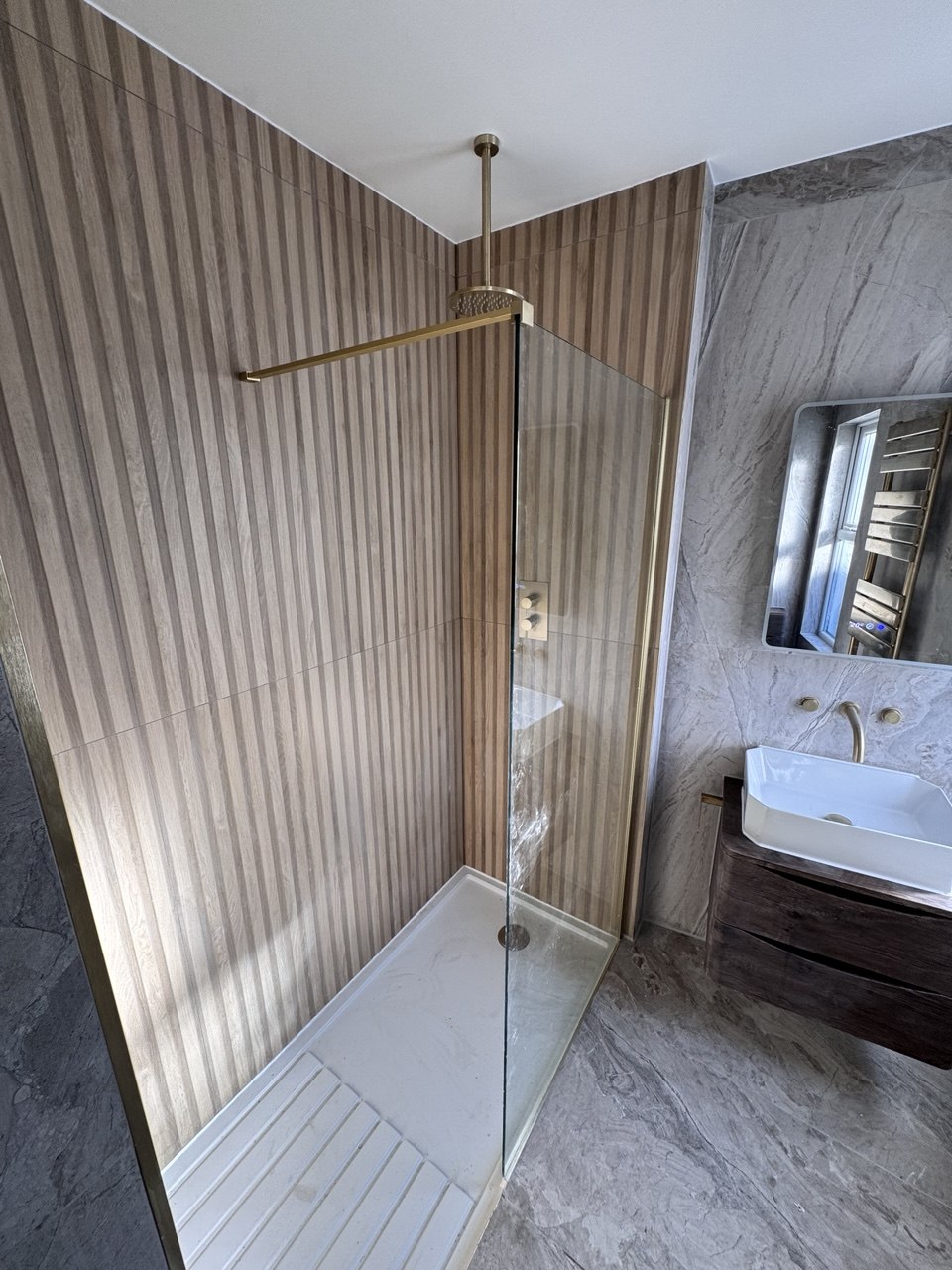 Walk-in shower with oak panelling and brushed gold rain head